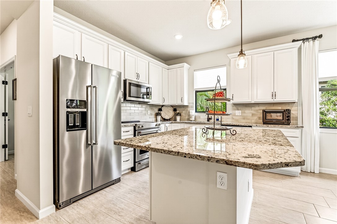 5191 Unity Square Vero Beach, FL 32967 - Photo 10 of 36 a kitchen with stainless steel appliances granite countertop a refrigerator a stove a sink and a refrigerator