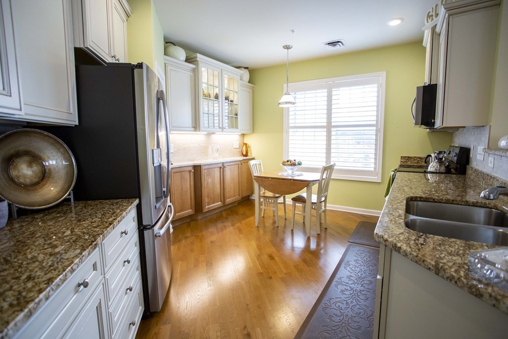 10 Abigail Way, Unit 3004 Reading, MA 01867 - Photo 16 of 32 a kitchen with sink refrigerator dining table and chairs