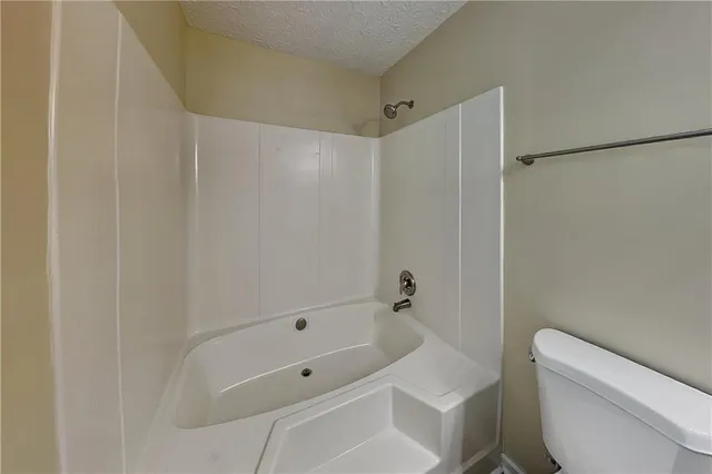 a bathroom with a tub shower and toilet