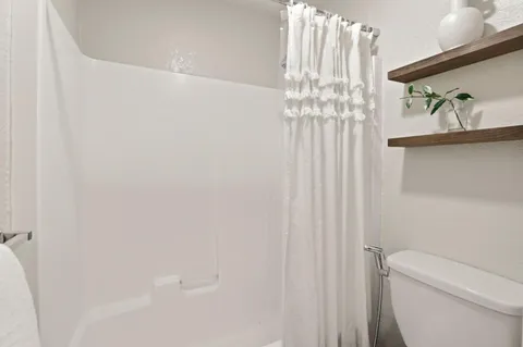 a bathroom with a toilet and a shower curtain
