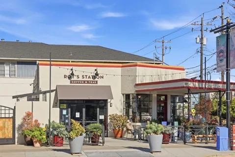 a view of a cafe with a couple of people seating on table and chairs