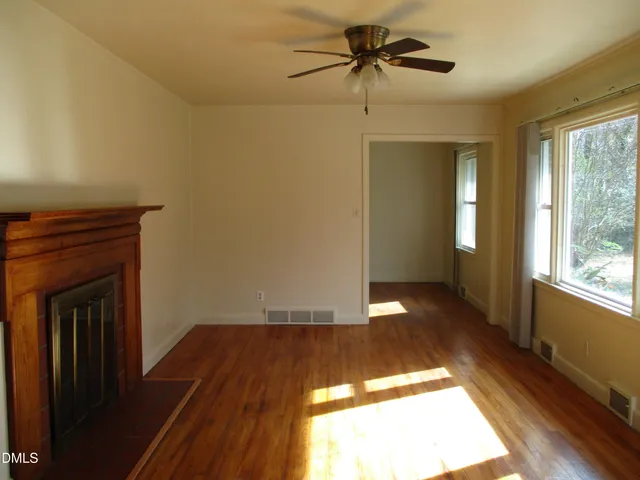 a view of empty room with wooden floor and fan