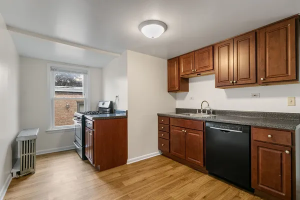 a kitchen with stainless steel appliances granite countertop wooden cabinets a sink a stove a refrigerator and dishwasher with wooden floor