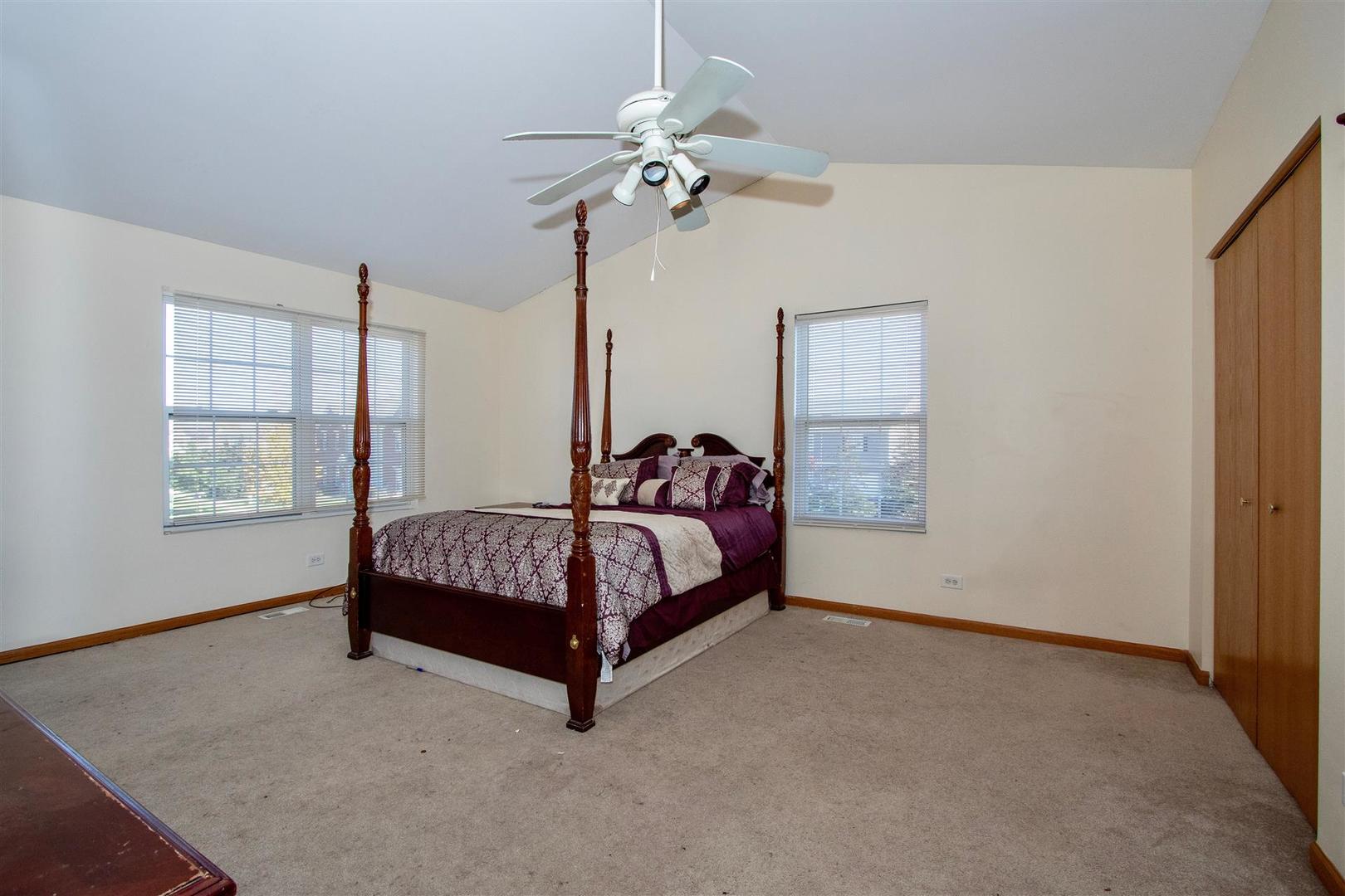 175 Springbrook Trail South Oswego, IL 60543 - Photo 8 of 25 a spacious bedroom with a bed and a chandelier