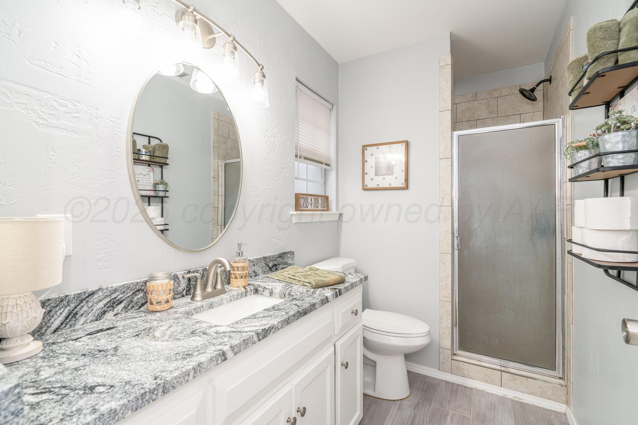 2205 Troveta Drive Amarillo, TX 79110 - Photo 20 of 28 a bathroom with a granite countertop sink toilet and a mirror