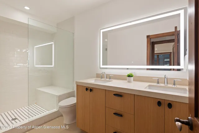 a bathroom with a toilet sink double vanity and mirror