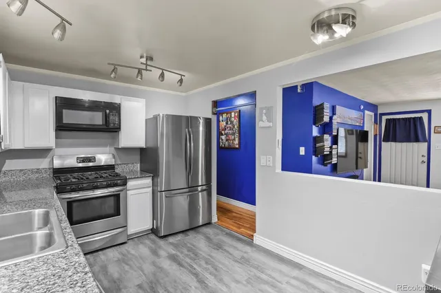 a kitchen with stainless steel appliances granite countertop a refrigerator a stove top oven a sink dishwasher and wooden floor