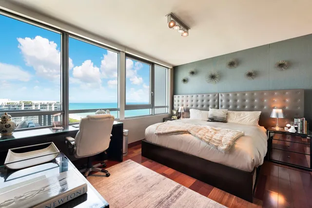 a bedroom with a bed a large window with table and chairs