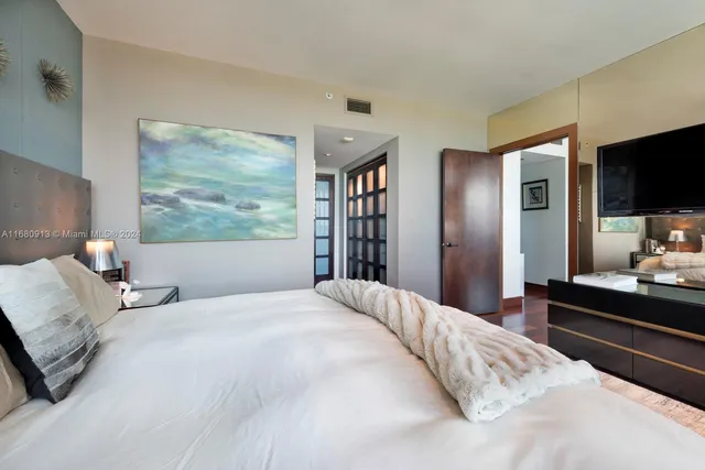 a bedroom with a large bed and a flat tv screen on a dresser