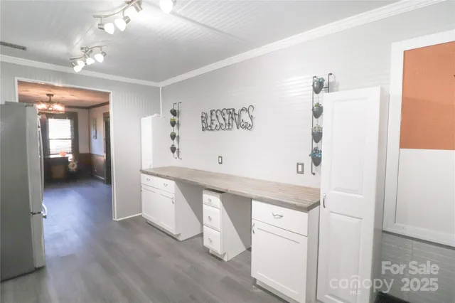 a hallway with white cabinets and wooden floor