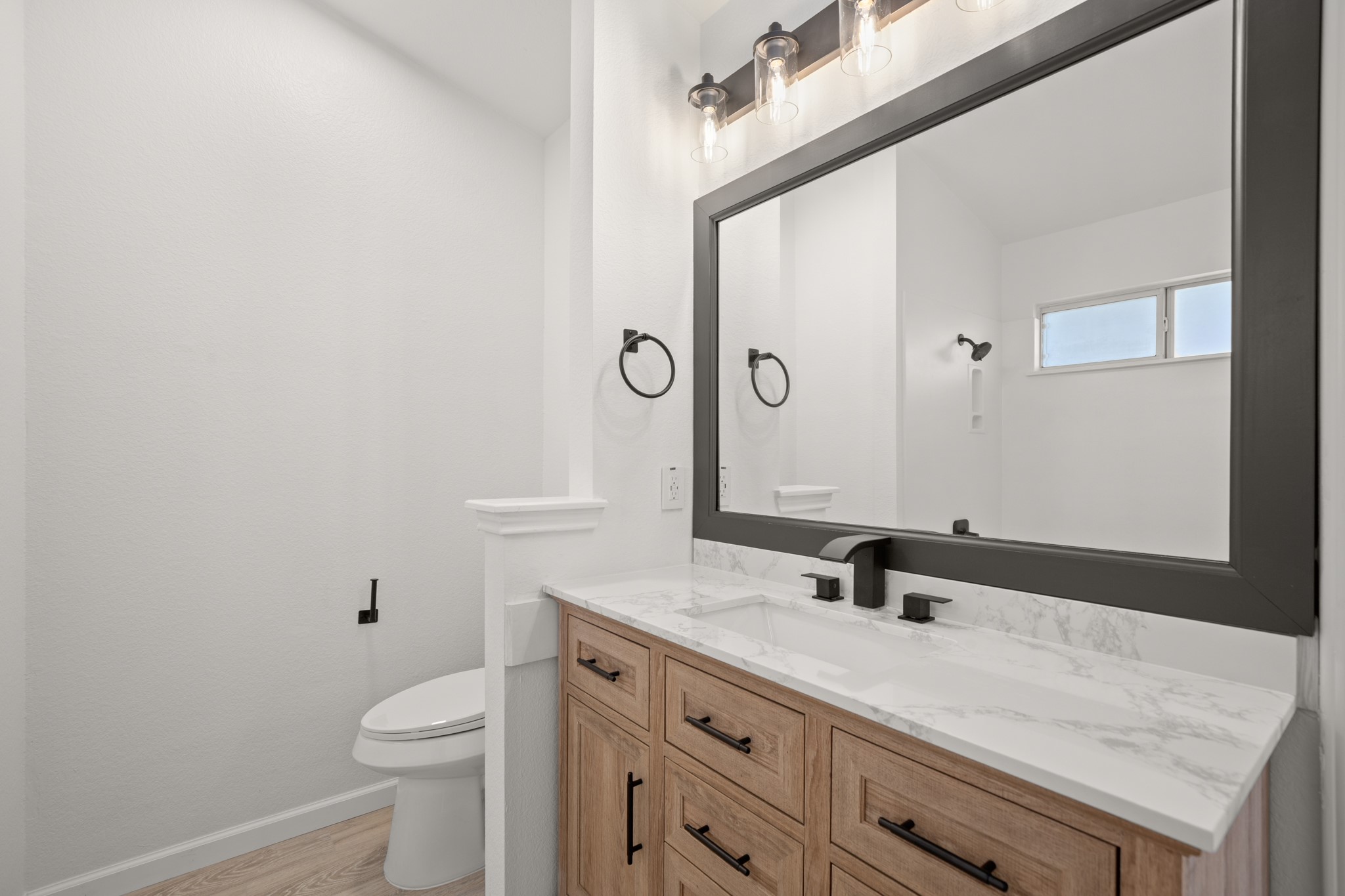 360 Sampson Kyle, TX 78640 - Photo 12 of 36 Bathroom with vanity featuring a light wood-finish cabinet with black hardware, a light-toned quartz countertop, and a rectangular sink