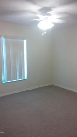 an empty room with chandelier fan and windows