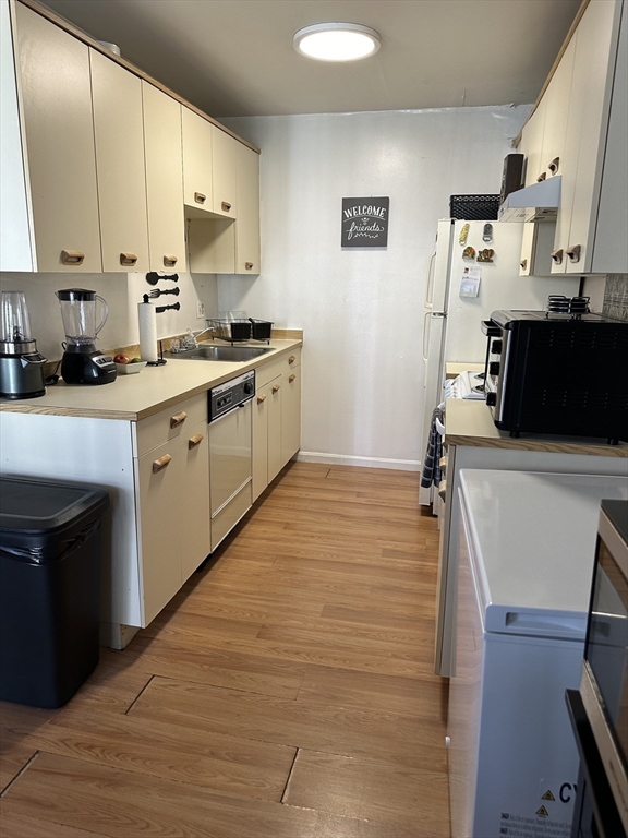 20 Knox Street, Unit 24 Lawrence, MA 01841 - Photo 4 of 13 a kitchen with stainless steel appliances a stove top oven a sink a refrigerator white cabinets and wooden floor