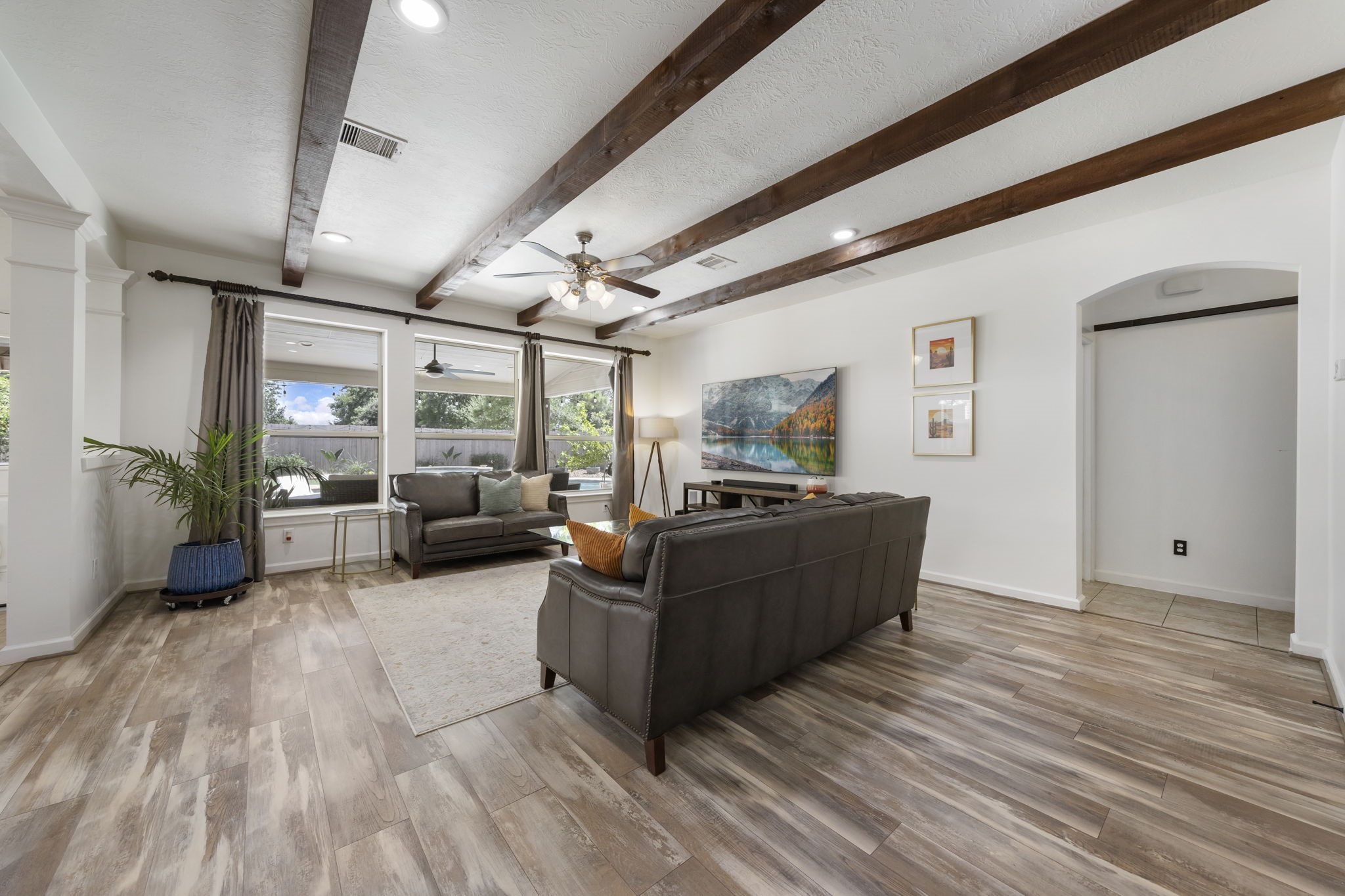 3318 Solvista High Court Spring, TX 77386 - Photo 8 of 33 Inviting family room showcases dramatic wood-beamed ceilings, expansive windows that overlook backyard pool, and an open-concept design that blends everyday comfort with effortless entertaining.