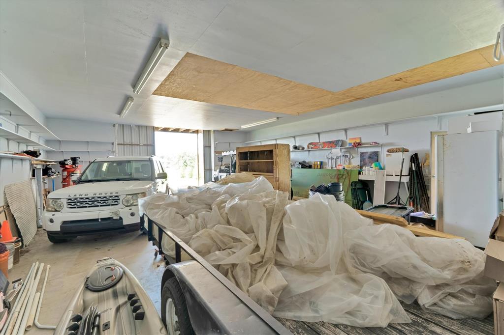 2717 Clear Lake Road Weatherford, TX 76087 - Photo 30 of 40 Spacious garage featuring a concrete floor, overhead fluorescent lighting, open shelving, and a large roll-up door
