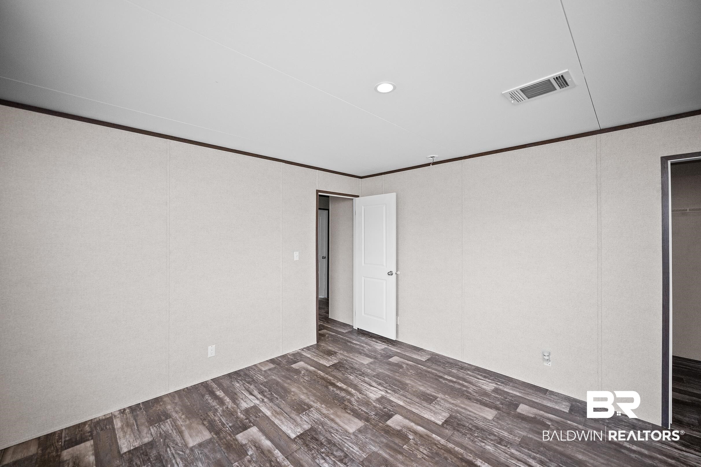 21601 Westside Loop Silverhill, AL 36576 - Photo 38 of 42 Spacious interior room featuring wood-finish flooring, light-toned wall panels, and contrasting dark trim