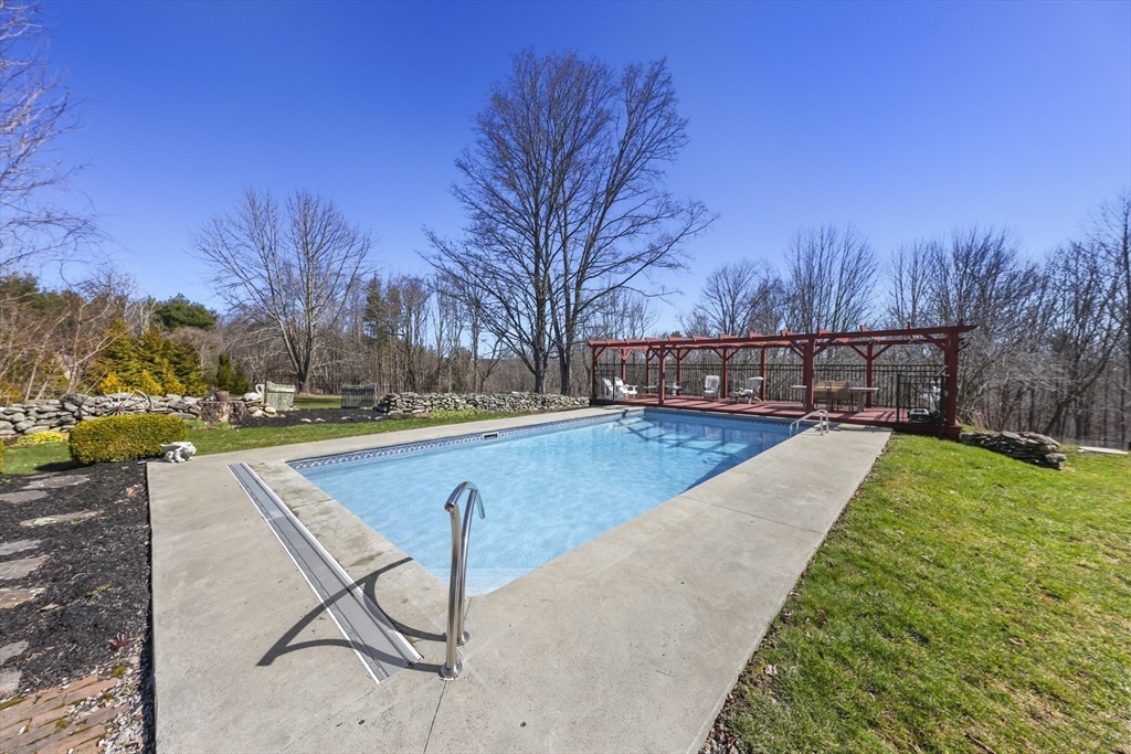 71 Prindle Hill Road Charlton, MA 01507 - Photo 39 of 40 a view of a swimming pool with a bench and trees