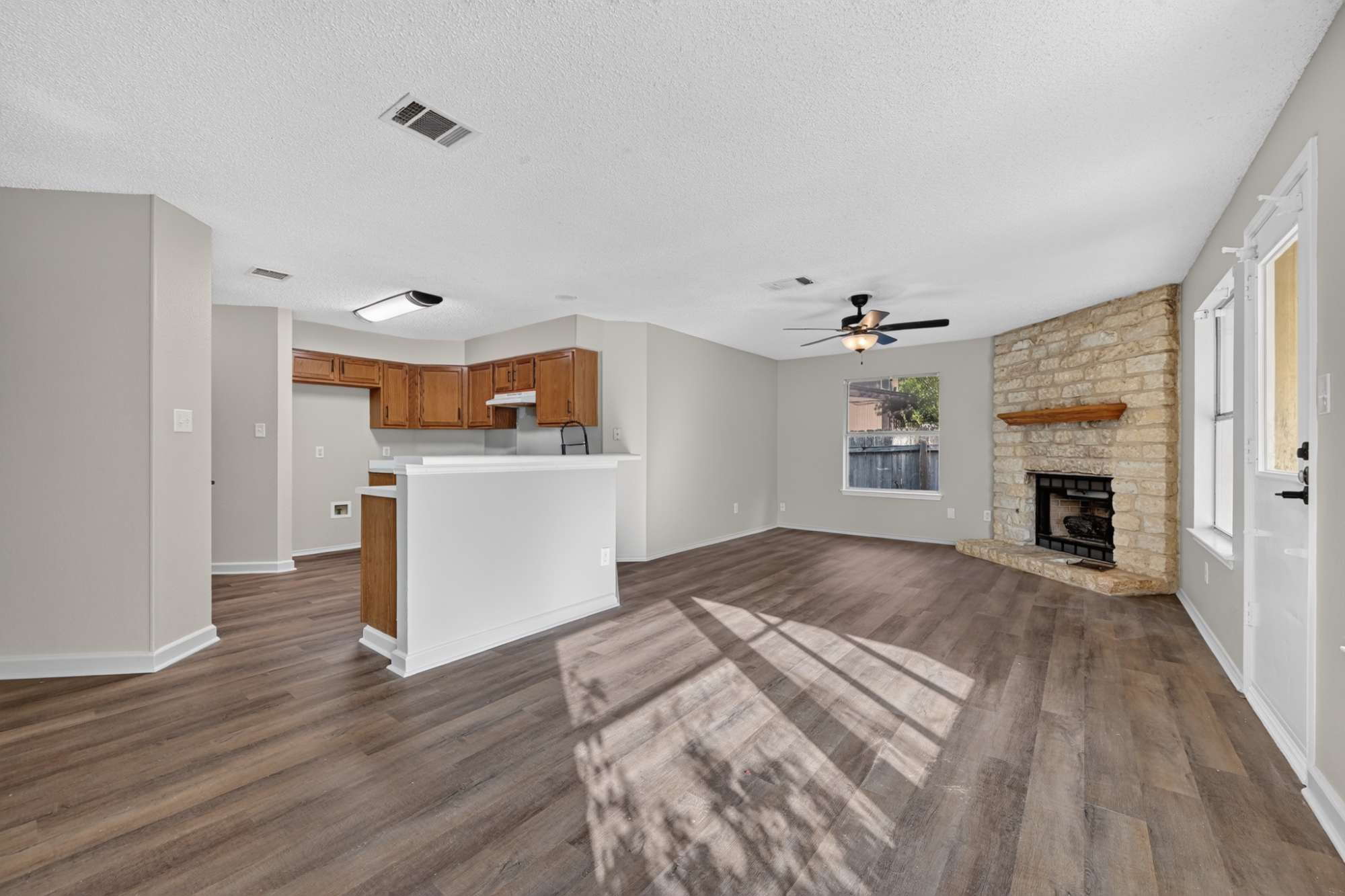 904 Nelson Ranch Road Cedar Park, TX 78613 - Photo 9 of 21 Rich wood-look flooring and a stone fireplace anchor this inviting open-concept living space.