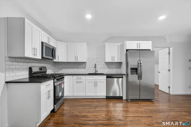 a large kitchen with stainless steel appliances granite countertop a stove a sink and a refrigerator