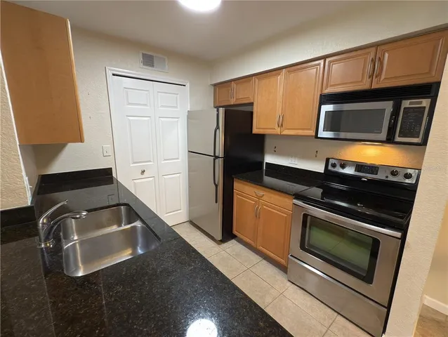 a kitchen with granite countertop a refrigerator and a sink