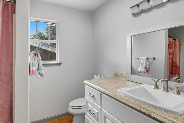 a bathroom with a granite countertop toilet sink and mirror