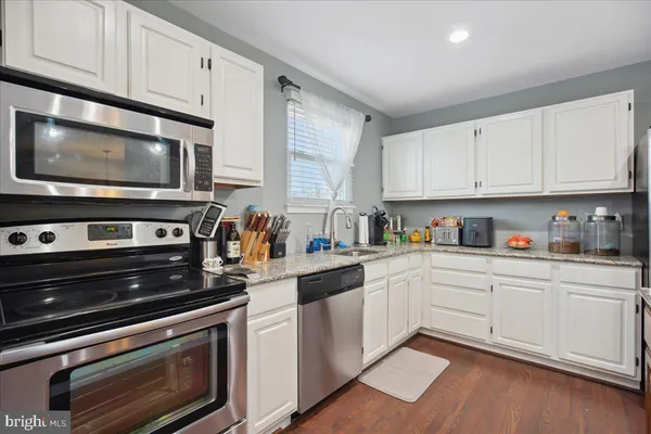 a kitchen with granite countertop white cabinets stainless steel appliances and a sink