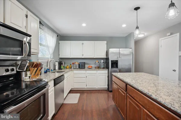 a kitchen with kitchen island white cabinets appliances and wooden floor