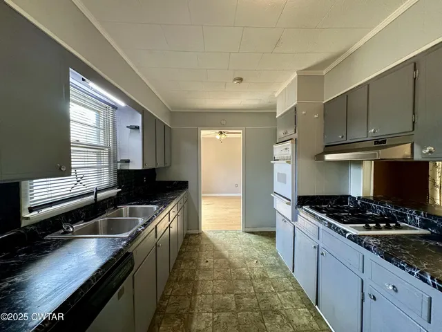 a kitchen with stainless steel appliances granite countertop a stove a sink and a microwave