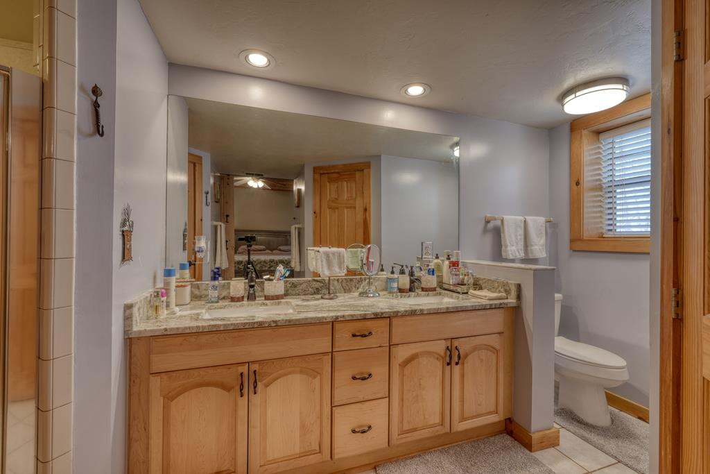 71 Andy Court Morganton, GA 30560 - Photo 15 of 43 a bathroom with a granite countertop sink a toilet a mirror a vanity and shower