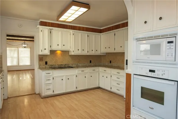 a kitchen with granite countertop white cabinets white stainless steel appliances and a sink