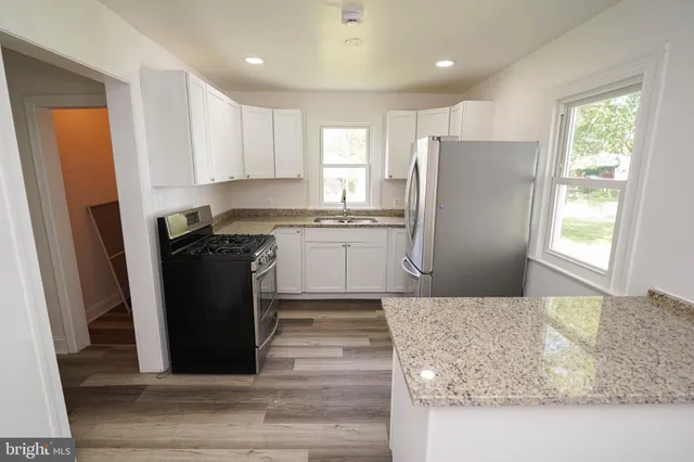 a kitchen with granite countertop a refrigerator a sink a stove and cabinets