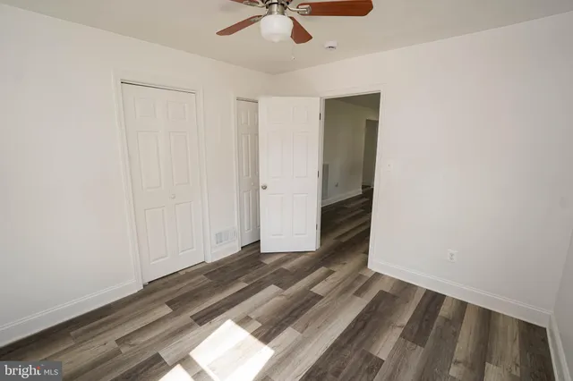 an empty room with wooden floor fan and windows