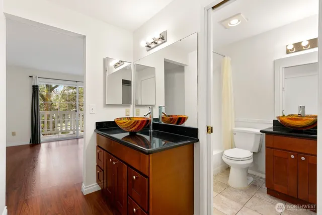 a bathroom with a granite countertop sink a toilet a mirror and shower