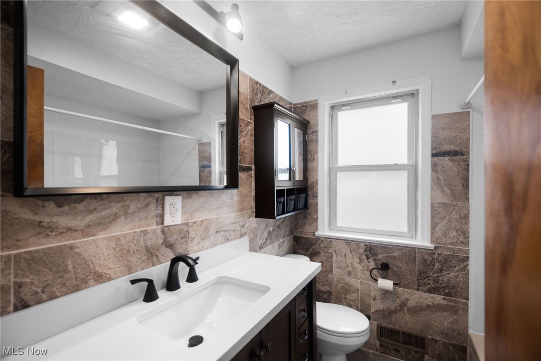 5618 Ackley Road Cleveland, OH 44129 - Photo 18 of 38 Bathroom with vanity, tile walls, toilet, and a textured ceiling