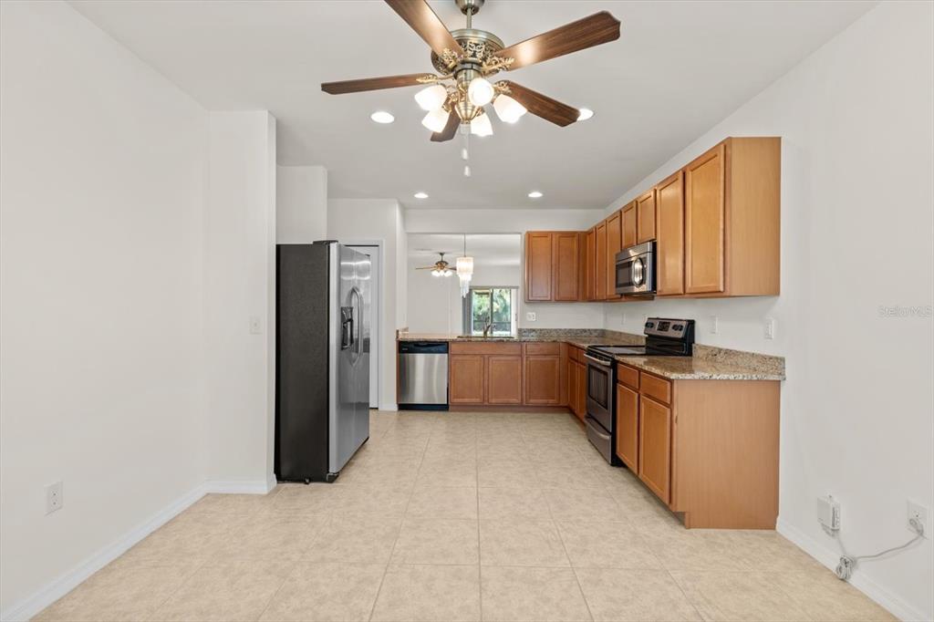 8932 Excelsior Place Venice, FL 34293 - Photo 12 of 43 a kitchen with stainless steel appliances granite countertop a refrigerator a sink dishwasher a stove with wooden cabinets