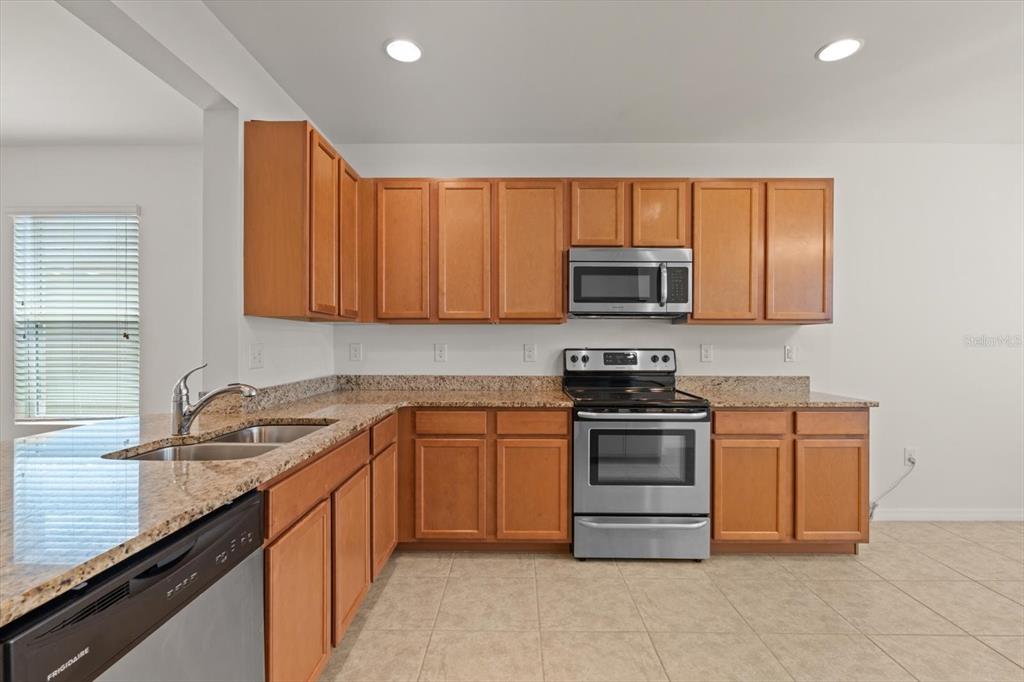 8932 Excelsior Place Venice, FL 34293 - Photo 8 of 43 a kitchen with stainless steel appliances granite countertop a sink stove and microwave