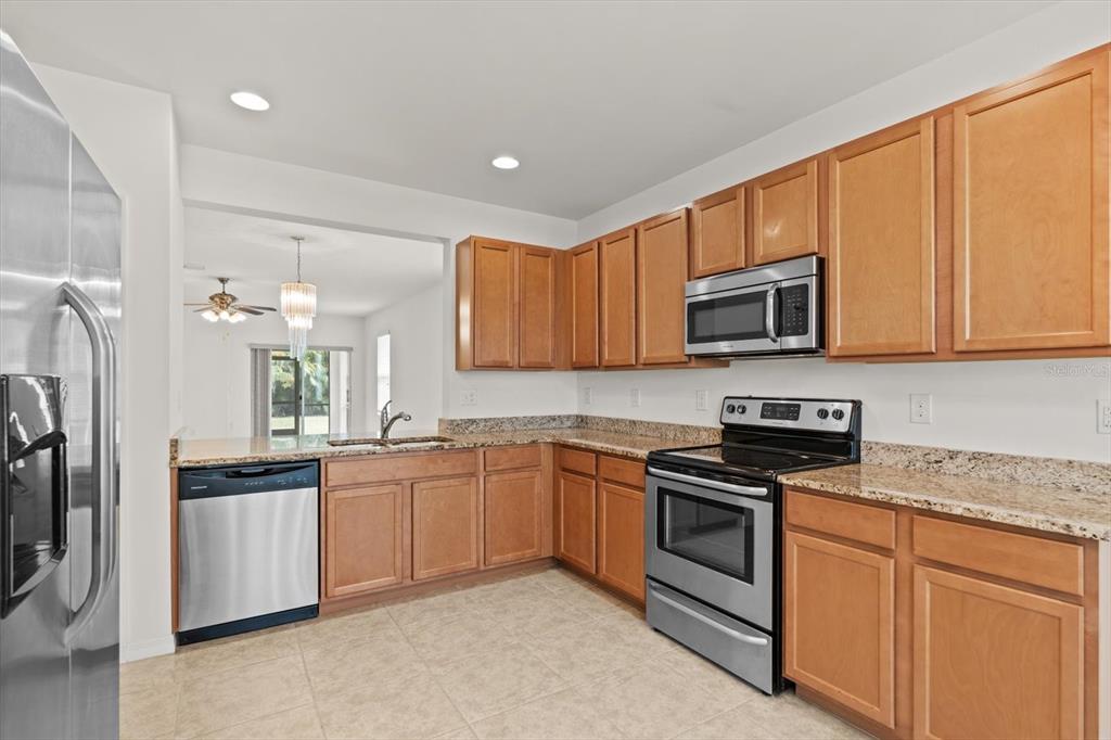 8932 Excelsior Place Venice, FL 34293 - Photo 10 of 43 a kitchen with stainless steel appliances granite countertop a stove top oven a sink dishwasher a refrigerator and a microwave