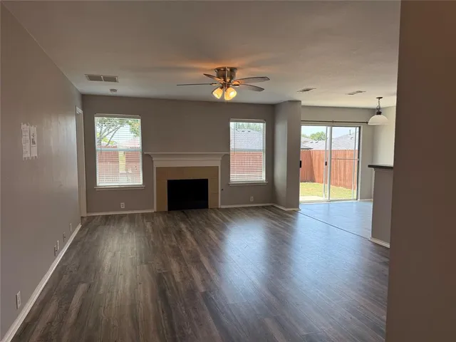 an empty room with wooden floor a fireplace and windows