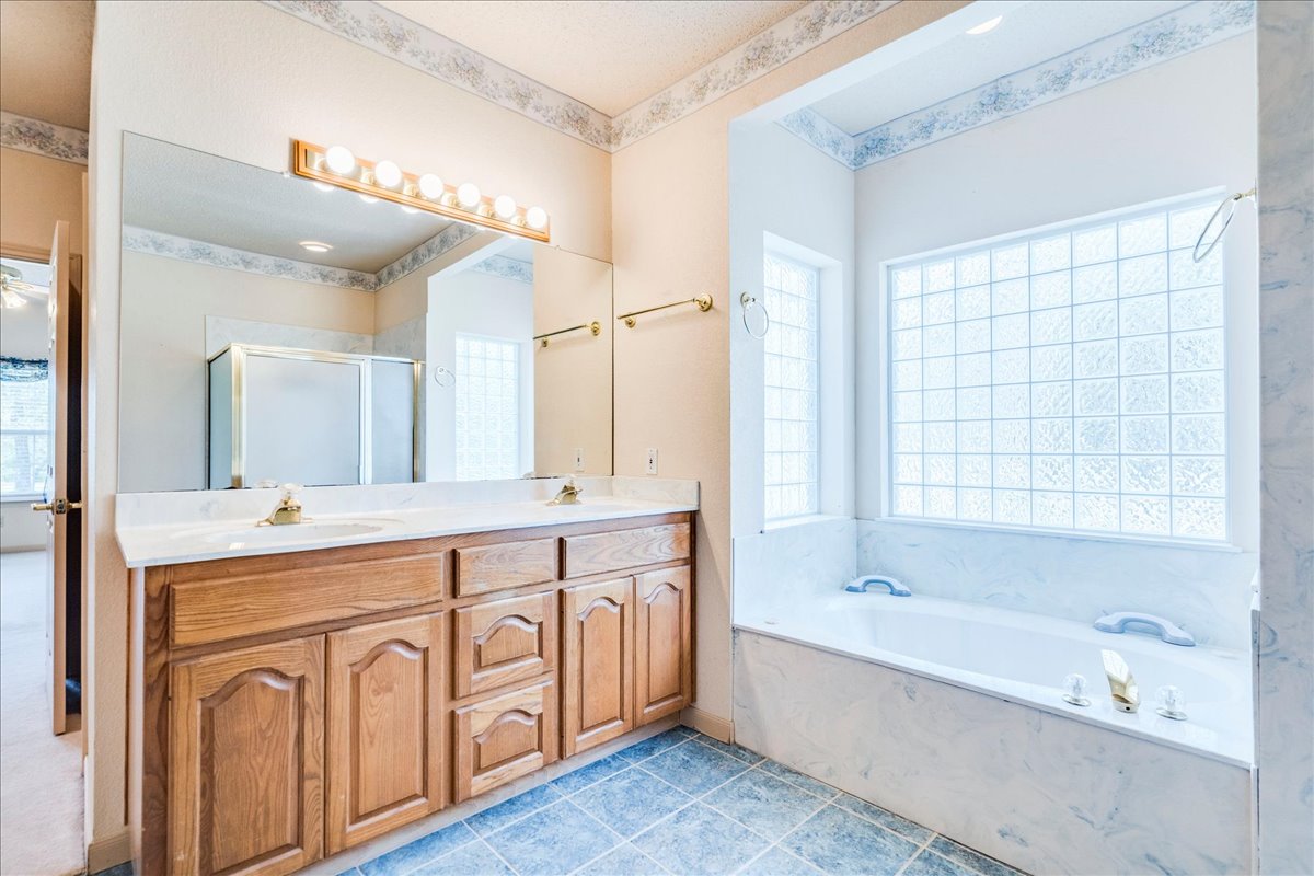 19106 Eyerley Road Manor, TX 78653 - Photo 16 of 40 Primary bathroom Double vanity and a deep soaking tub create a luxurious bathroom retreat.