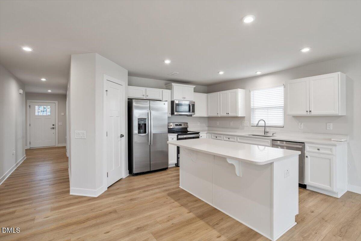 8588 Kenridge Lane Fuquay-Varina, NC 27526 - Photo 12 of 37 a large kitchen with stainless steel appliances granite countertop a stove a sink a refrigerator and white cabinets with wooden floor