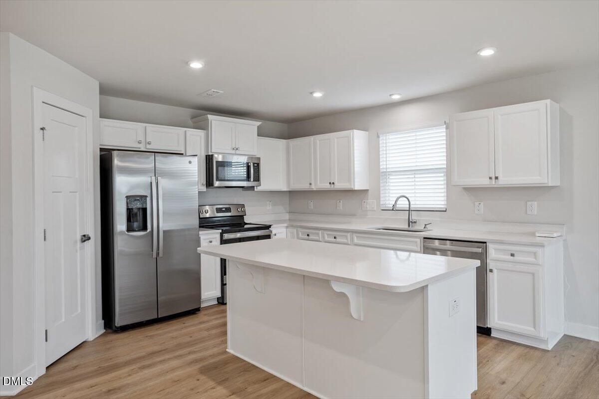 8588 Kenridge Lane Fuquay-Varina, NC 27526 - Photo 13 of 37 a kitchen with a refrigerator a sink a stove a microwave and cabinets