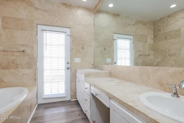 a bathroom with a granite countertop sink a bathtub and window