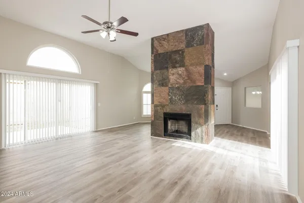 an empty room with windows a fireplace and a chandelier fan
