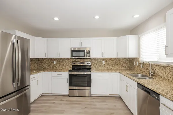 a kitchen with stainless steel appliances granite countertop a refrigerator and a sink