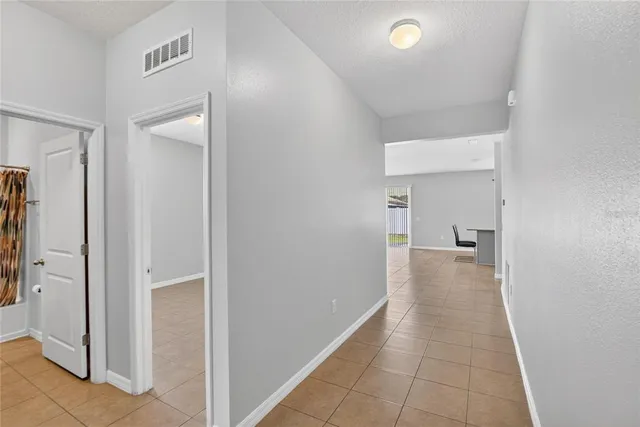 a view of a hallway with wooden floor and a bathroom