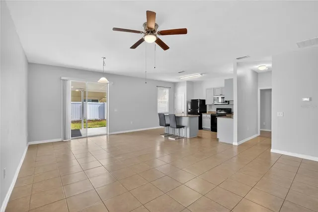 a view of a livingroom with kitchen furniture and a ceiling fan