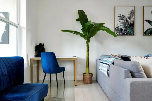 a living room with furniture kitchen view and a potted plant