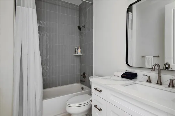 a bathroom with a bathtub shower sink mirror vanity and toilet