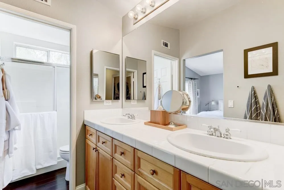 7730 Corte Marin Carlsbad, CA 92009 - Photo 16 of 26 a bathroom with a double vanity sink and a mirror