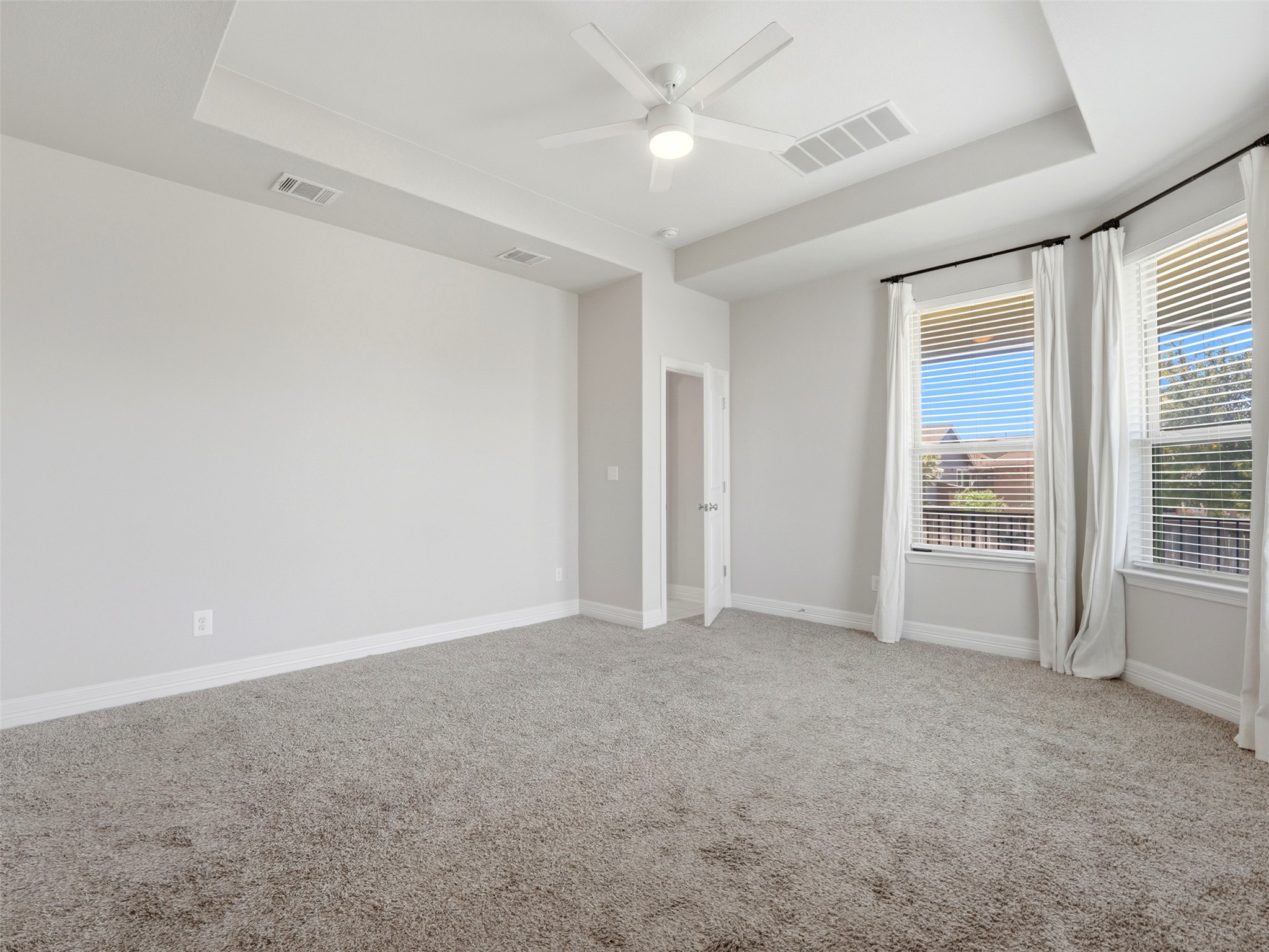 2132 Ringstaff Road Leander, TX 78641 - Photo 21 of 39 A spacious bedroom features plush carpet and an elegant tray ceiling with a modern ceiling fan.